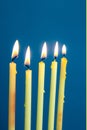 Five burning thin candles on a blue background Royalty Free Stock Photo
