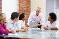 Five businesspeople in boardroom with laptop