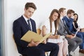 Five candidates sit waiting for job interviews, close up