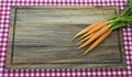 Five carrots on wooden board and tablecloth.