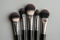 Five clean makeup brushes are displayed on a gray background, ready for applying cosmetics Royalty Free Stock Photo