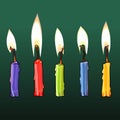 Five colorful burning candles on green background