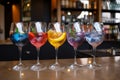 Five colorful gin tonic cocktails in wine glasses on bar