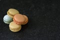 Five colorful macaroons in a pile on a black background. Five tasty cookies