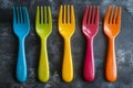 Five colorful plastic forks are arranged on a dark gray surface, adding a vibrant pop of color to the scene Royalty Free Stock Photo