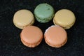 Five colourful macaroons are on the black background. Five tasty cookies