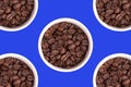 Five cups with coffee grains on a blue background, cutout. Royalty Free Stock Photo