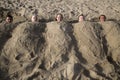 Five cute happy caucasian children buried on the sand on the beach Royalty Free Stock Photo