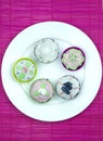 Five decorated muffins on a wooden and pink placemat