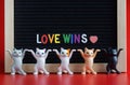 Five different colorful dancing toy kittens next to the inscription love wins. Red background. The concept of a pacifist LGBT