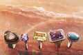 Five different gold rings with precious stones on a marble surface