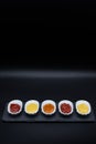Five different sauces on buffet in small bowls with black background