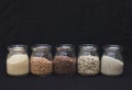 Five different types of cereals in jars on a black background. Porridge. Healthy food Royalty Free Stock Photo
