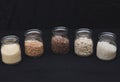 Five different types of cereals in jars on a black background. Porridge. Healthy food Royalty Free Stock Photo