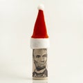 A five-dollar US bill is rolled into a tube and a red cap at the top. President Lincoln is like Santa Claus. New Year or Christmas Royalty Free Stock Photo