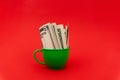 Five dollars in green cup at red background. Royalty Free Stock Photo
