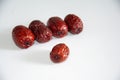 Five dried red dates arranged in a staggered pattern, with a deep red wrinkled skin and a white background Royalty Free Stock Photo