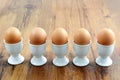 Five egg cups with natural brown eggs in a row on table Royalty Free Stock Photo