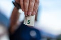 Five euro folded in a focused hand in foreground