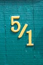 Five fraction one. Slash. Yellow numbers on wooden painted green boards. House number on the fence close-up. Vertical Royalty Free Stock Photo
