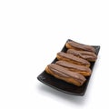 Five fresh eclairs with chocolate icing are on a black rectangular plate.