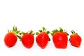 Five fresh and natural red strawberries of different shapes with green leaves, side by side, on white background