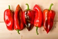 Five fresh organic red peppers on a raw wooden table ready to be cooked, top view or flat lay of healthy vegan food Royalty Free Stock Photo