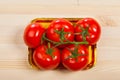 Five fresh red tomatoes with green stem in the tray , isolated on the background Royalty Free Stock Photo