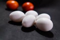 Five fresh white eggs and tomatoes on black surface Royalty Free Stock Photo