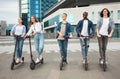 Five friends having pleasant ride on motorized kick scooters Royalty Free Stock Photo