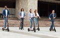 Five friends having pleasant ride on motorized kick scooters Royalty Free Stock Photo