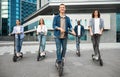 Five friends having ride on motorized kick scooters Royalty Free Stock Photo
