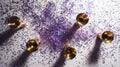 Five golden shot glasses arranged in a circle on a white surface covered in purple glitter Royalty Free Stock Photo