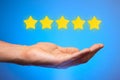 Five golden yellow stars out of five. Man holds star on the palm of his hand, puts rating, reviews