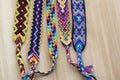 Five handmade homemade colorful natural woven bracelets of friendship on wooden board, group of fashion accessories