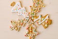 Five herringbone gingerbread cookies, differently decorated with glaze and sprinkles, set against a white painted wood