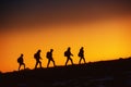 Five hikers going uphill at sunset