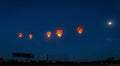 Five hot air balloons are flying over a baseball field