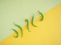 five isolated green chili peppers on a yelow surface Royalty Free Stock Photo