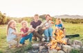 Five kids group Boys and girls cheerfully laughed and roasted sausages on sticks over a campfire flame near the green tent. Royalty Free Stock Photo