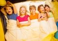 Five kids lay under blanket