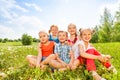 Five kids smile sitting on a grass