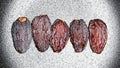 Five large dried dates on black and white background