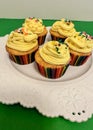 Five lemon cupcakes with yellow frosting with sprinkles on white plate Royalty Free Stock Photo