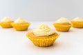 Five frosted cupcakes against a white light background