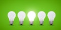 Five light bulbs in a row, center light bulb is brightly lit. Green background.