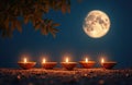 Five lit diyas glow on a sandy surface under a large full moon. Tree branches frame the serene night sky creating a festive and Royalty Free Stock Photo
