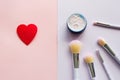 Five makeup brushes with lettering on the handle and mineral powder in a blue jar, red felt brooch