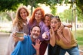 Five mature adults taking a selfie and having fun in a park.