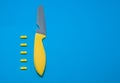 Yellow knife and five pills side by side on a blue background